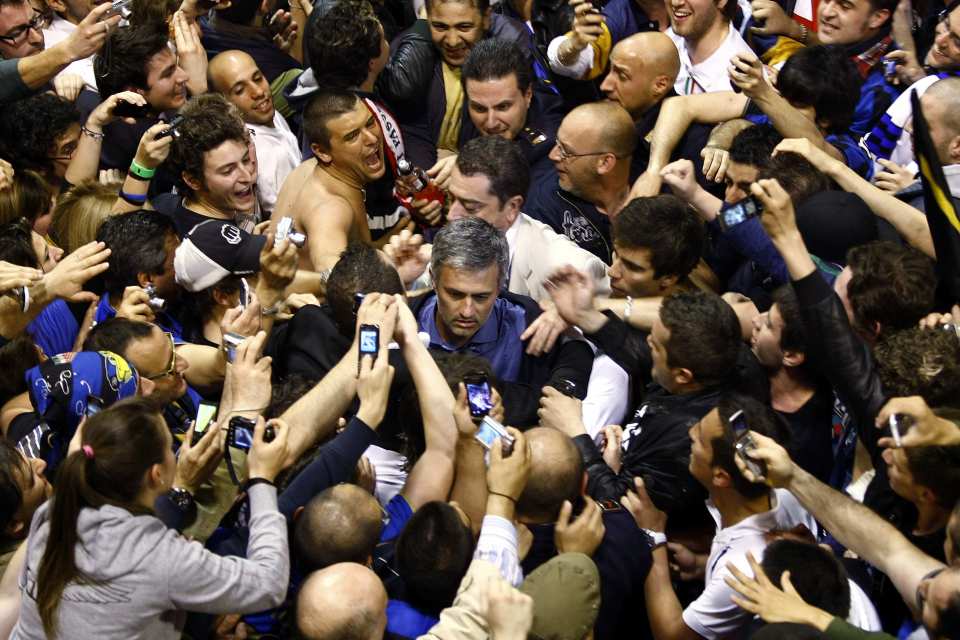 Inter Milan's coach Jose Mourinho (C) is surrounded by fans as he arrives from Barcelona, at Malpensa airport around 40 km (25 miles) northwest from Milan April 29, 2010. Inter Milan battled for more than an hour with 10 men to cling on against Barcelona on Wednesday, eliminating the holders 3-2 on aggregate to advance to next month's Champions League final. REUTERS/Alessandro Garofalo (ITALY - Tags: SPORT SOCCER)