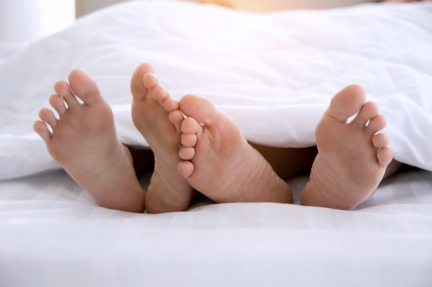 a couple 's feet sticking out from under a white blanket