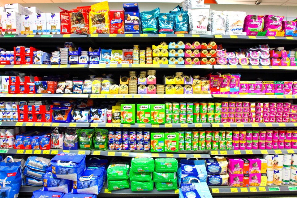 Supermarket shelf stocked with various cat food products.