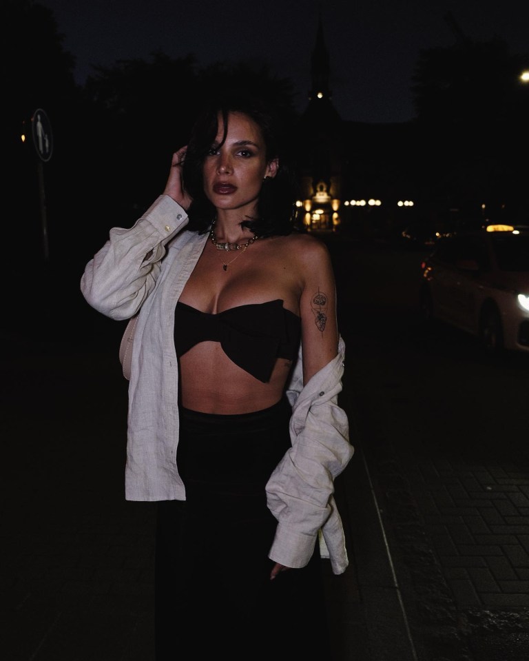 a woman with a tattoo on her arm is standing in the dark