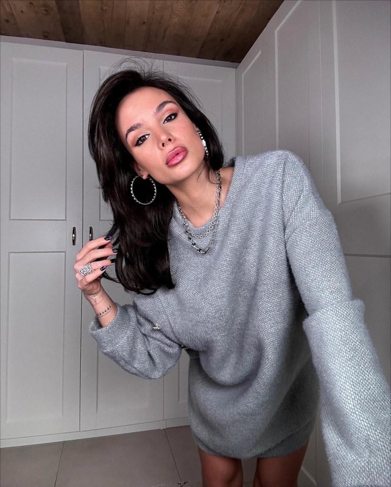 a woman wearing a grey sweater and hoop earrings