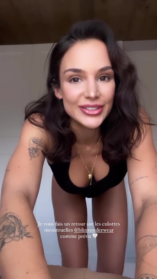 a woman with a tattoo on her arm is wearing a black top