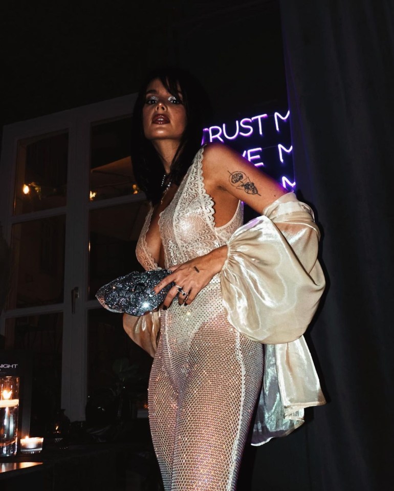 a woman stands in front of a neon sign that says trust me