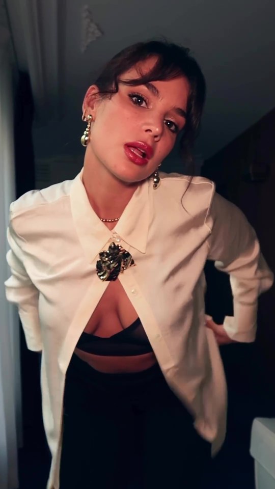 a woman wearing a white shirt with a brooch on it