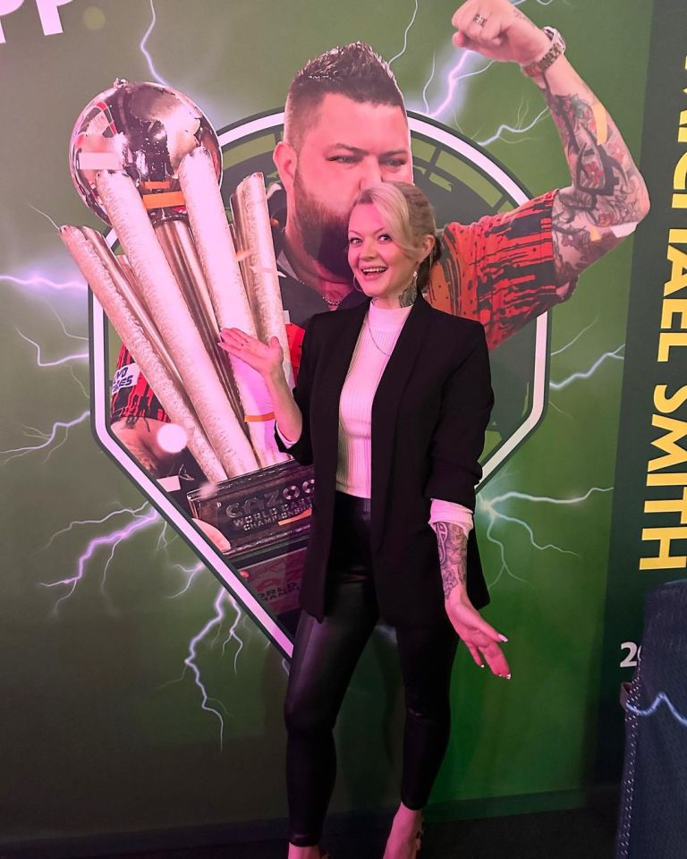 Woman posing with a large trophy and a Michael Smith backdrop.