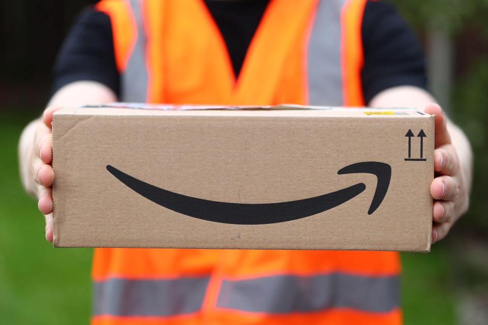 Delivery person holding an Amazon package.