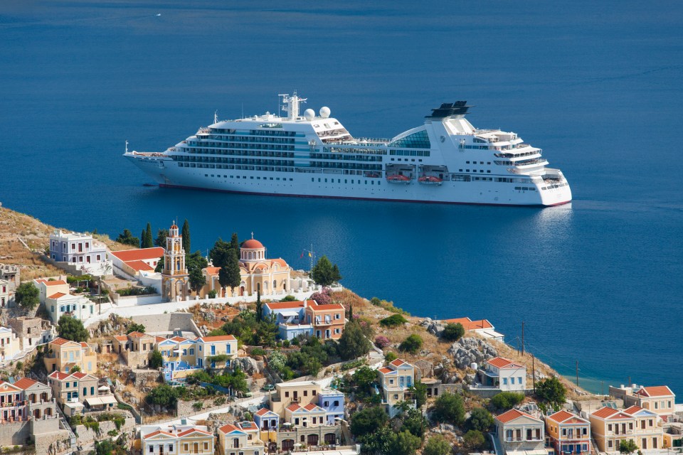 a cruise ship is floating in the ocean near a small town