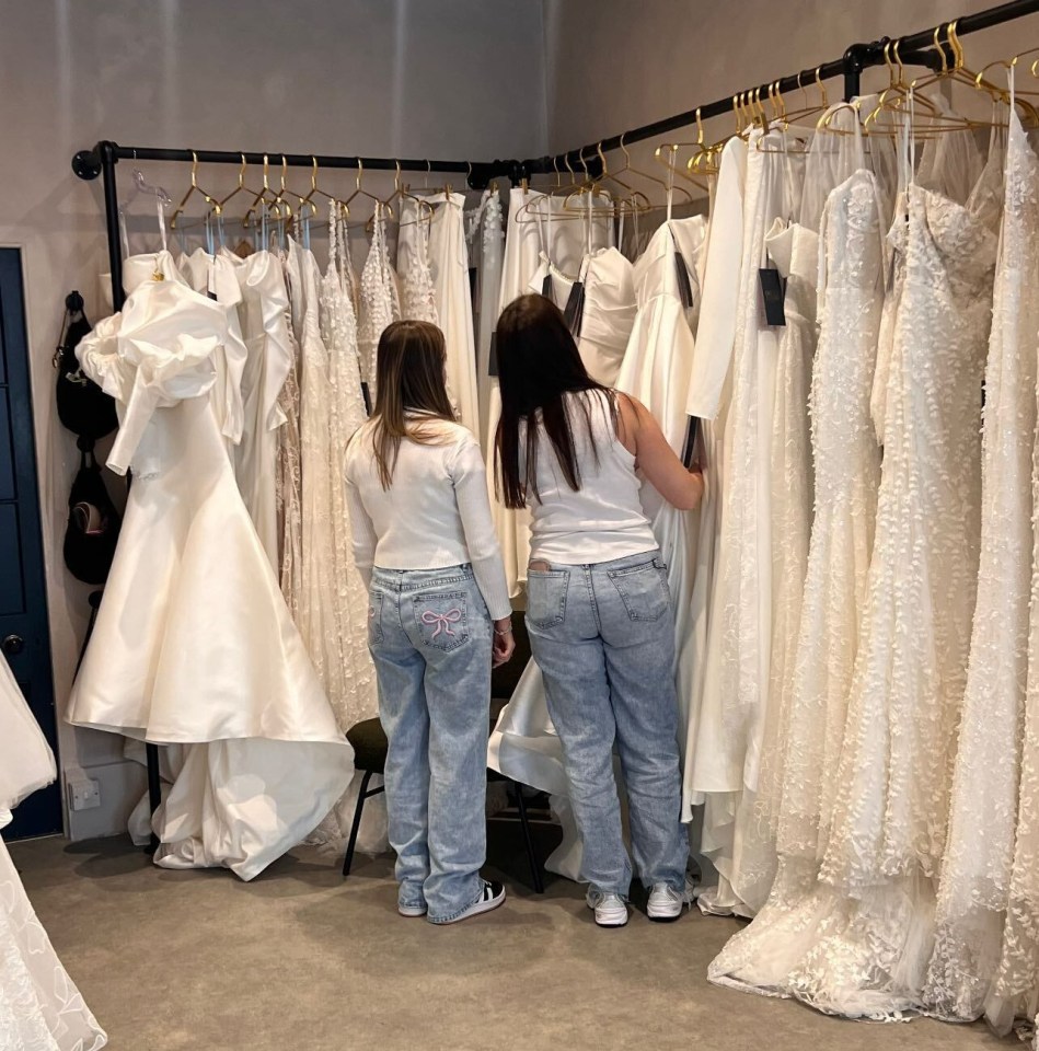 two women are looking at wedding dresses in a store