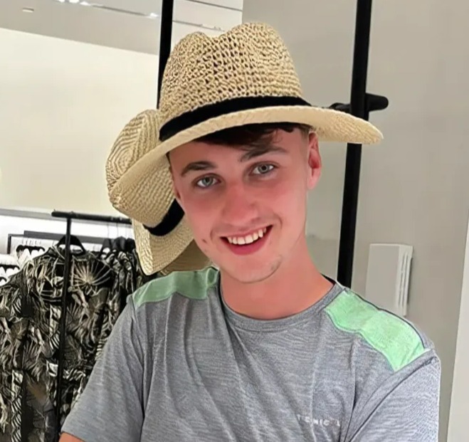 a young man wearing a straw hat and a t-shirt with the word atomic on it