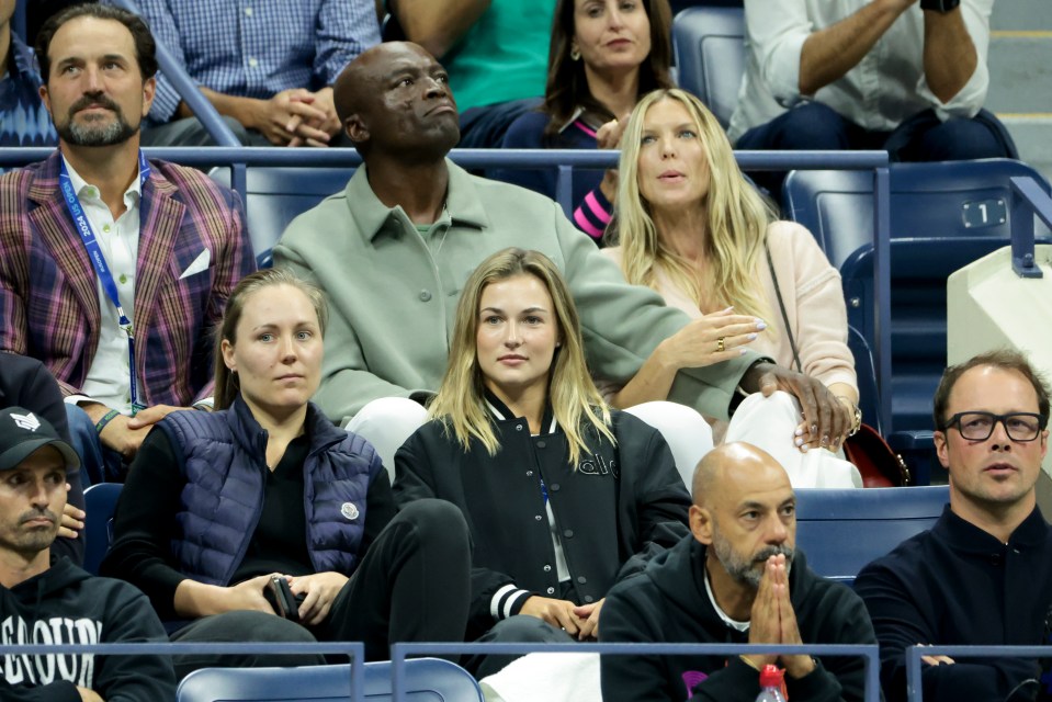 a group of people sitting in a stadium with one wearing a sweater that says good