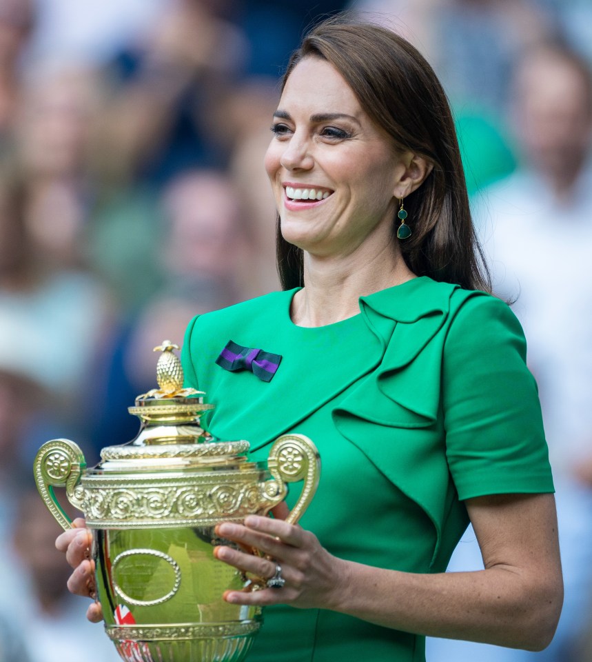 a woman in a green dress is holding a trophy