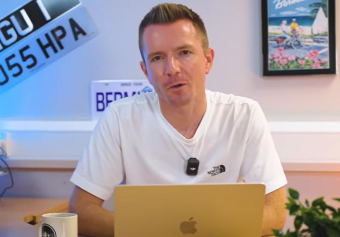 a man wearing a north face shirt is sitting in front of an apple laptop