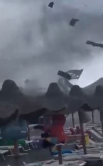 a group of people are standing under a tent during a storm .