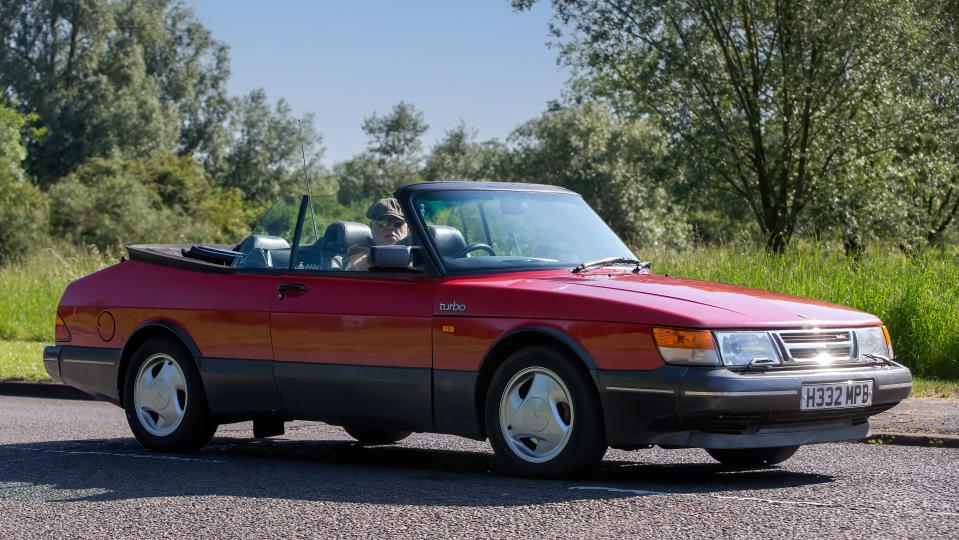 a red saab turbo convertible is parked on the side of the road