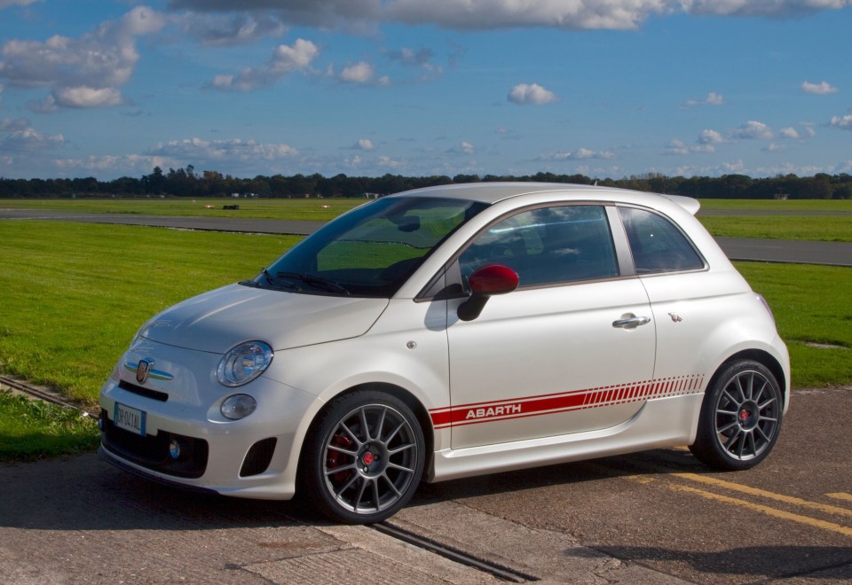 a white abarth car is parked on the side of the road