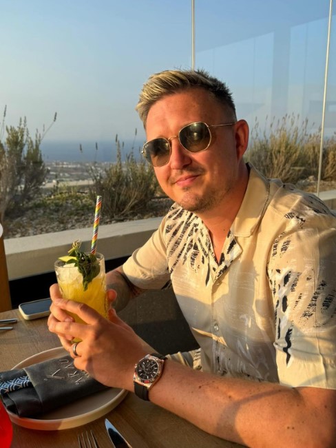 a man sitting at a table holding a drink with a straw