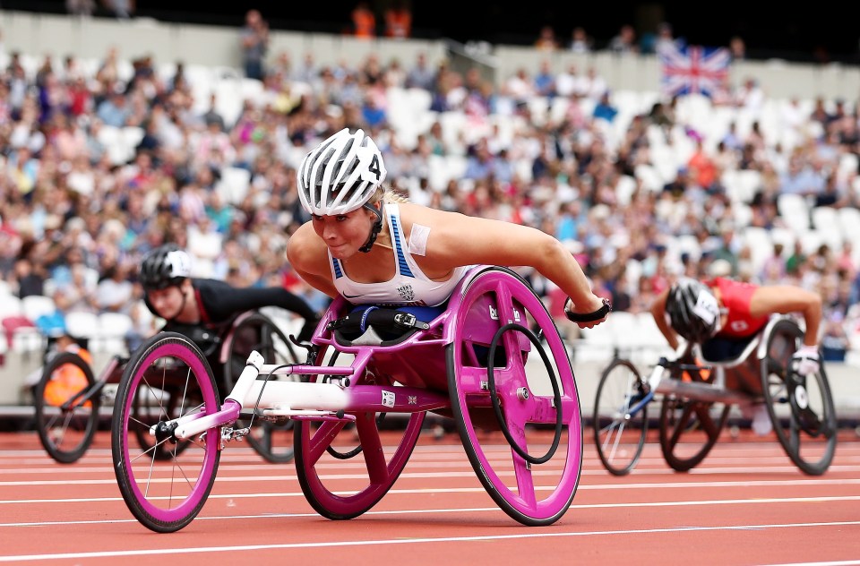 a woman in a pink wheelchair is racing on a track