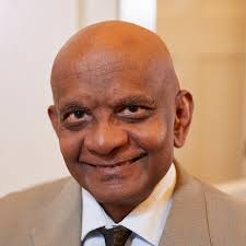 a bald man in a suit and tie is smiling for the camera .