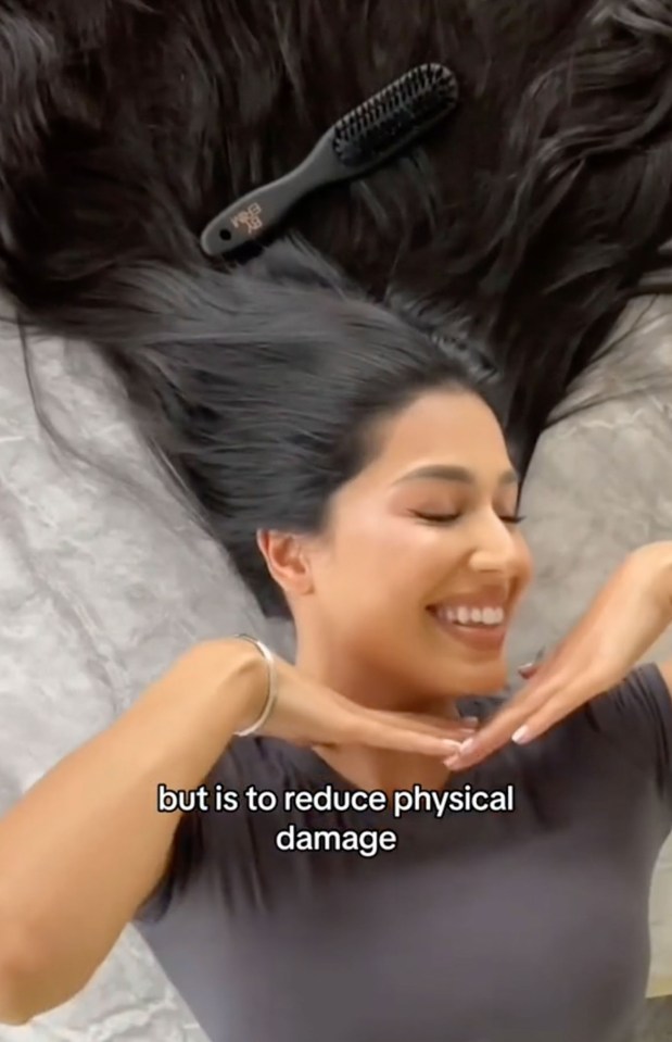 a woman is laying on her back with a brush in her hair .