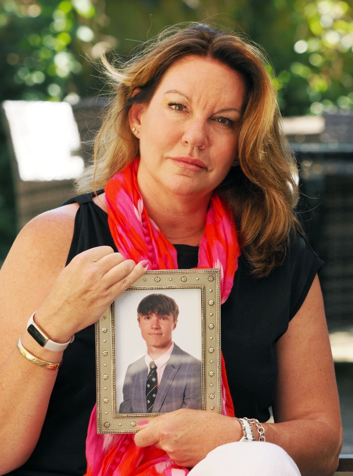 a woman holds a picture of a young man in a suit and tie