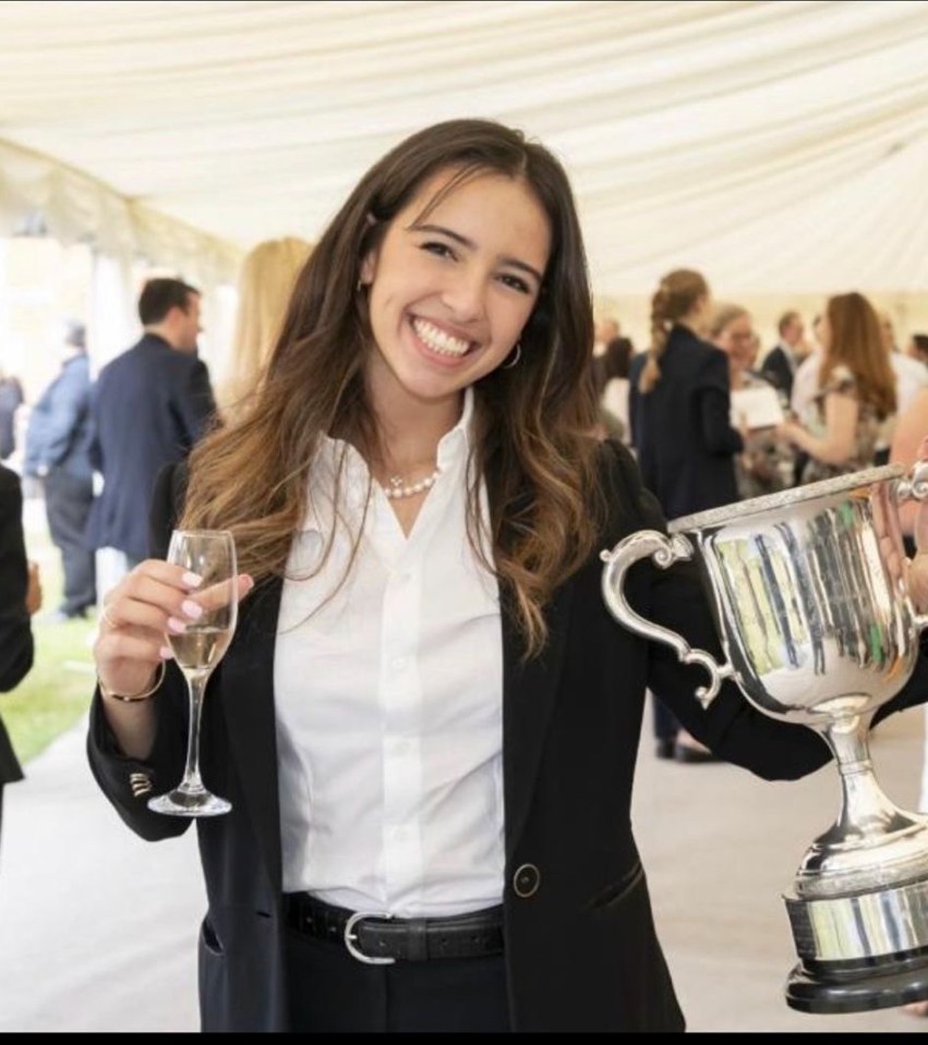a woman holding a trophy and a glass of wine