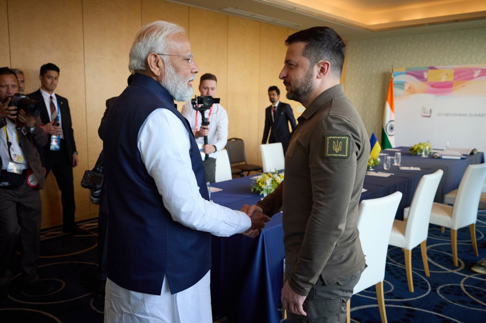 two men are shaking hands in front of a wall that says india summit