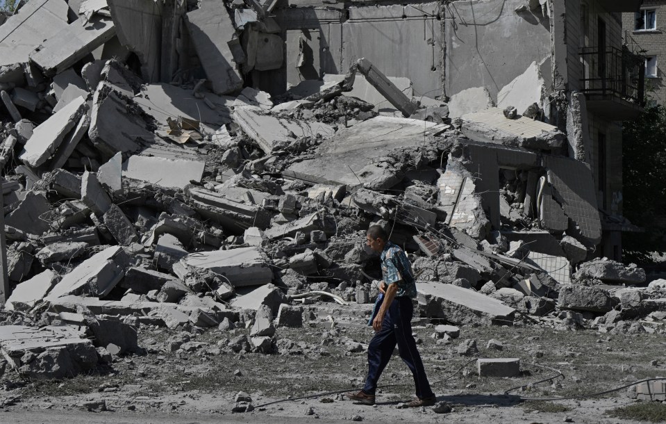a man walking in front of a pile of rubble