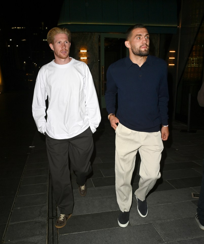 a man in a white shirt stands next to another man in a blue sweater