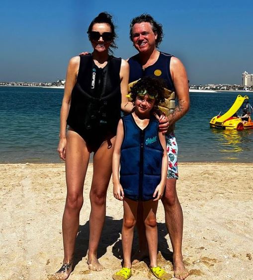 a man , a woman and a child are standing on a beach .