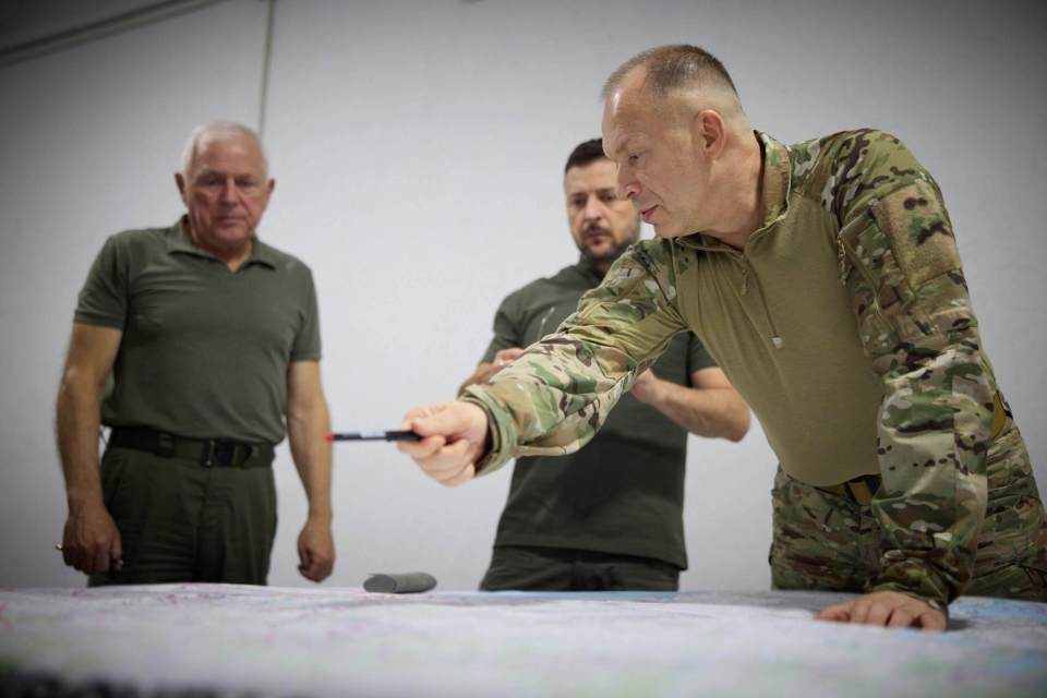 three men in military uniforms are looking at a map