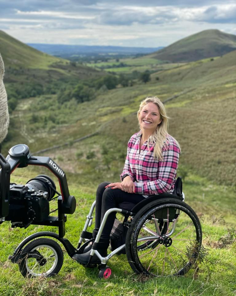 a woman in a wheelchair is smiling in front of a ronin camera