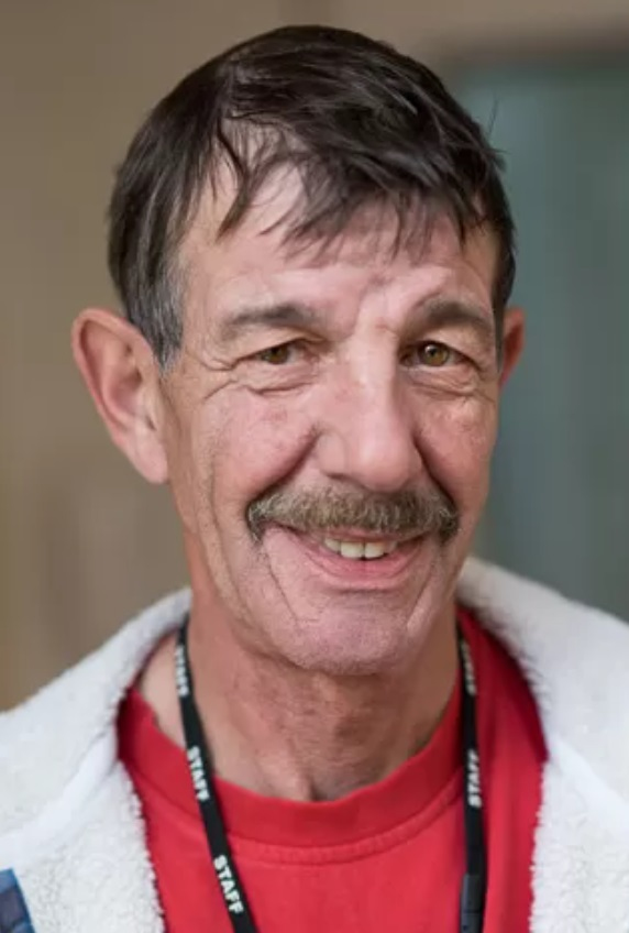 a man with a mustache is wearing a lanyard that says staff on it .