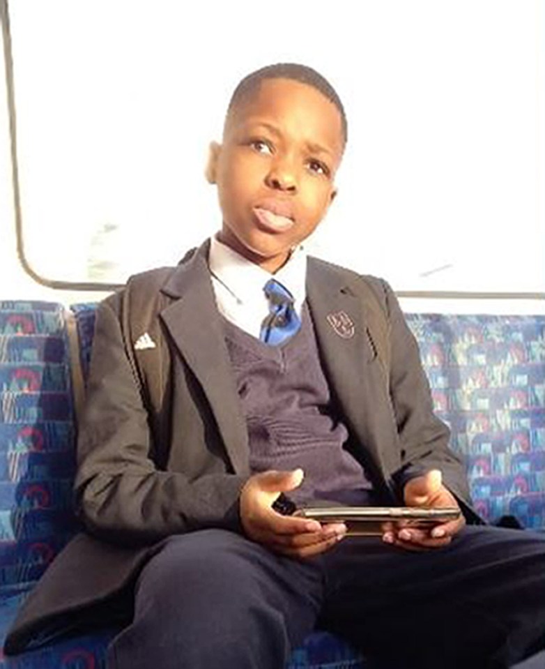 a young boy in a school uniform is sitting on a bus holding a tablet .