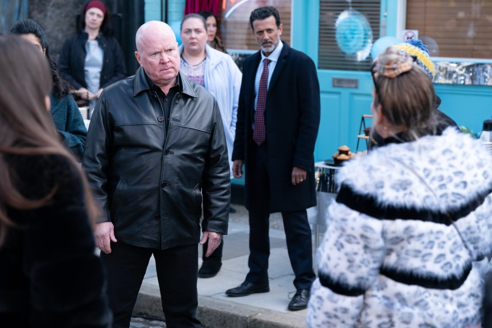 a man in a black leather jacket stands in front of a group of people