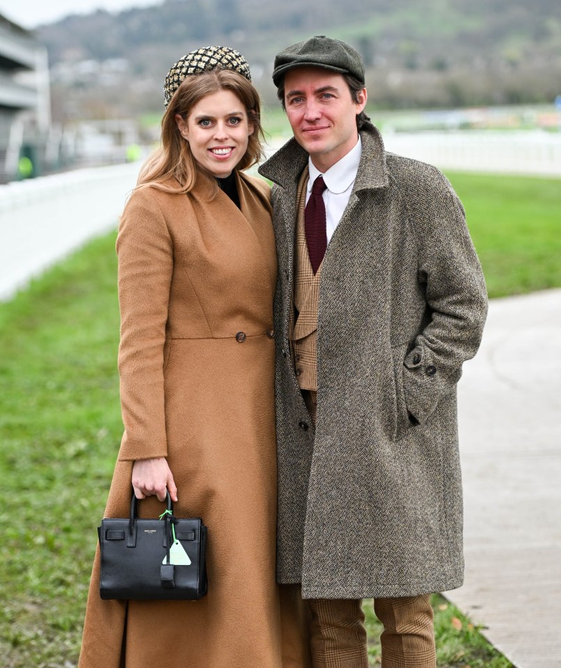 a woman in a brown coat holds a black bag that says yves saint laurent