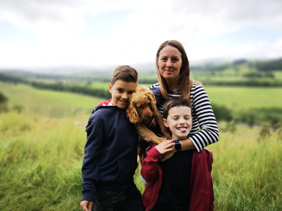 a woman holds a puppy while two children look on