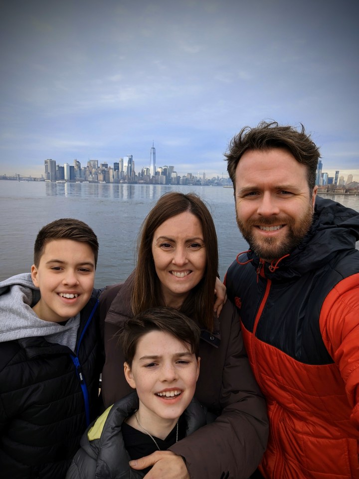 a family posing for a picture with the new york city skyline in the background