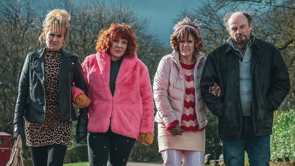 a group of people standing next to each other with one wearing a pink fur coat
