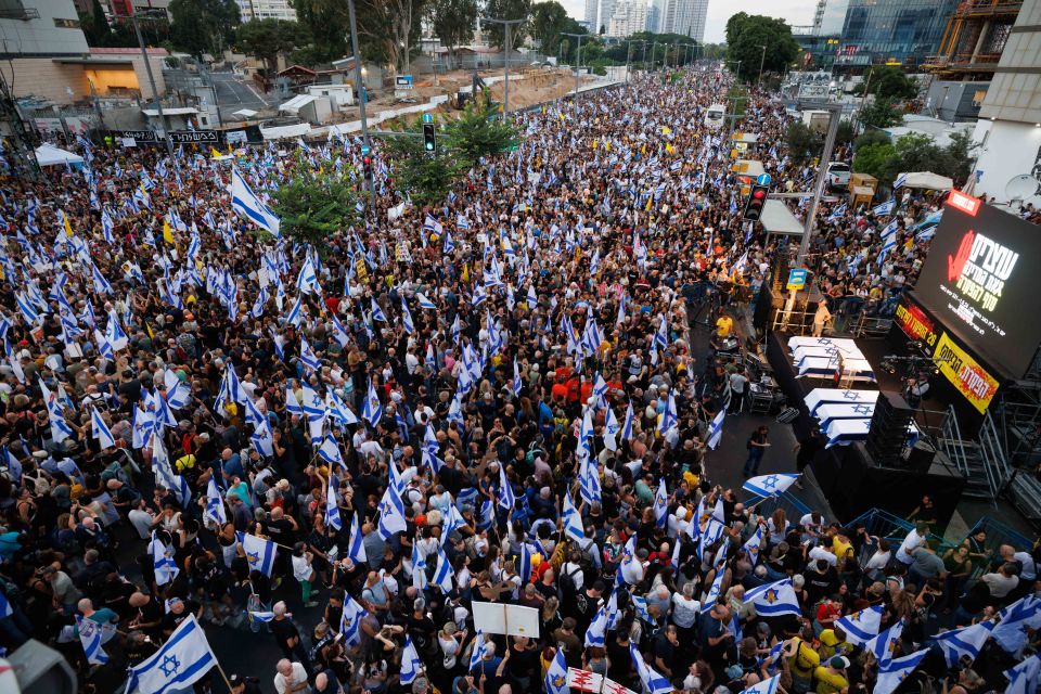 a large crowd of people holding flags in front of a large screen that says ' aviv ' on it