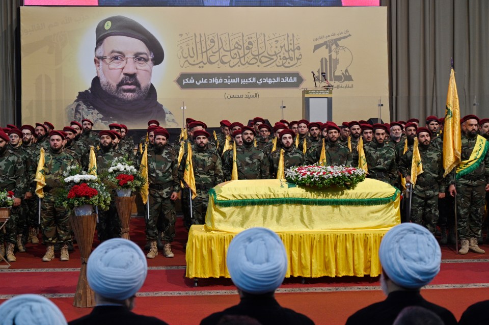 a group of men in military uniforms stand around a yellow coffin