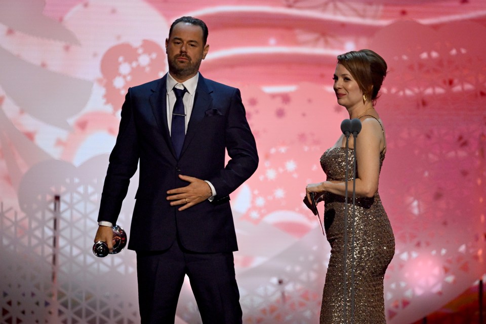a man in a suit and tie stands next to a woman in a gold dress