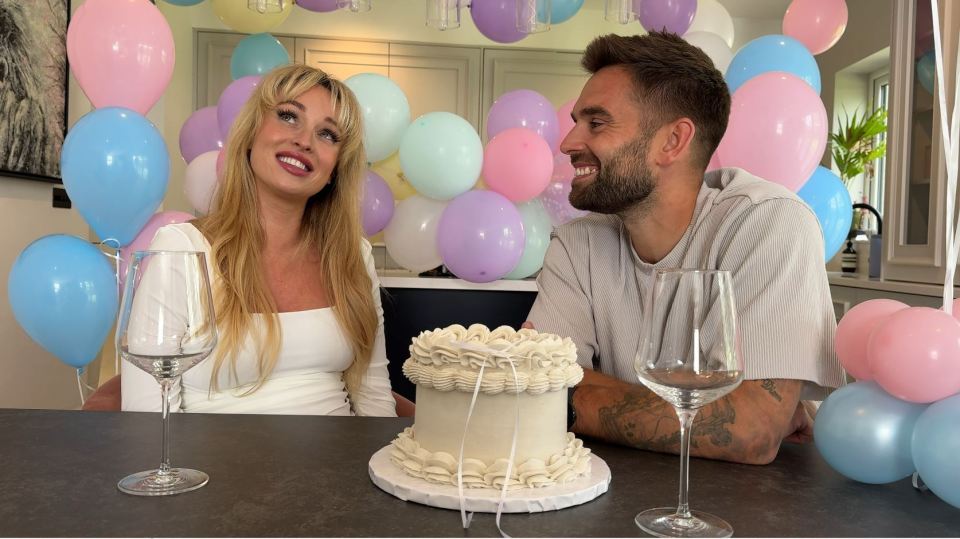 a man and a woman sit at a table with a cake and wine glasses