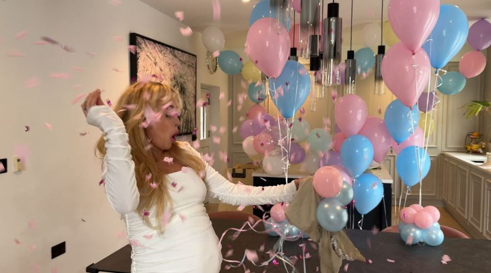 a woman in a white dress is surrounded by pink and blue balloons