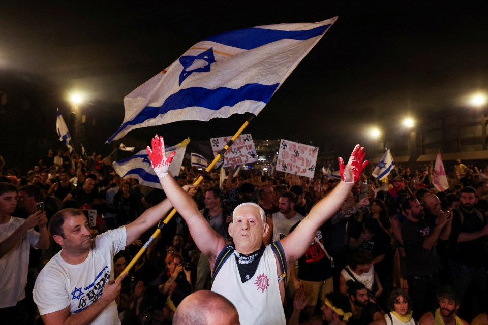 a man wearing a mask holds up a flag in front of a crowd