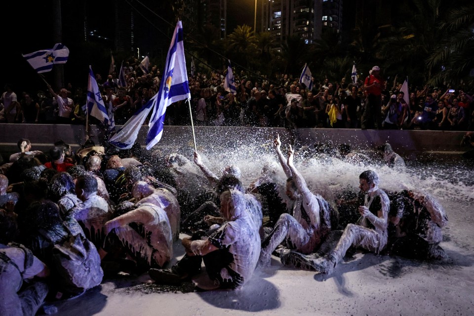 a group of people are covered in foam and holding flags