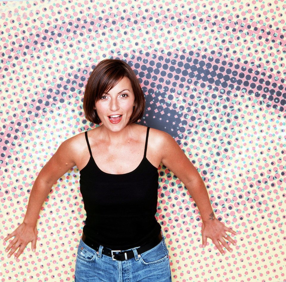 a woman in a black tank top stands in front of a polka dot background