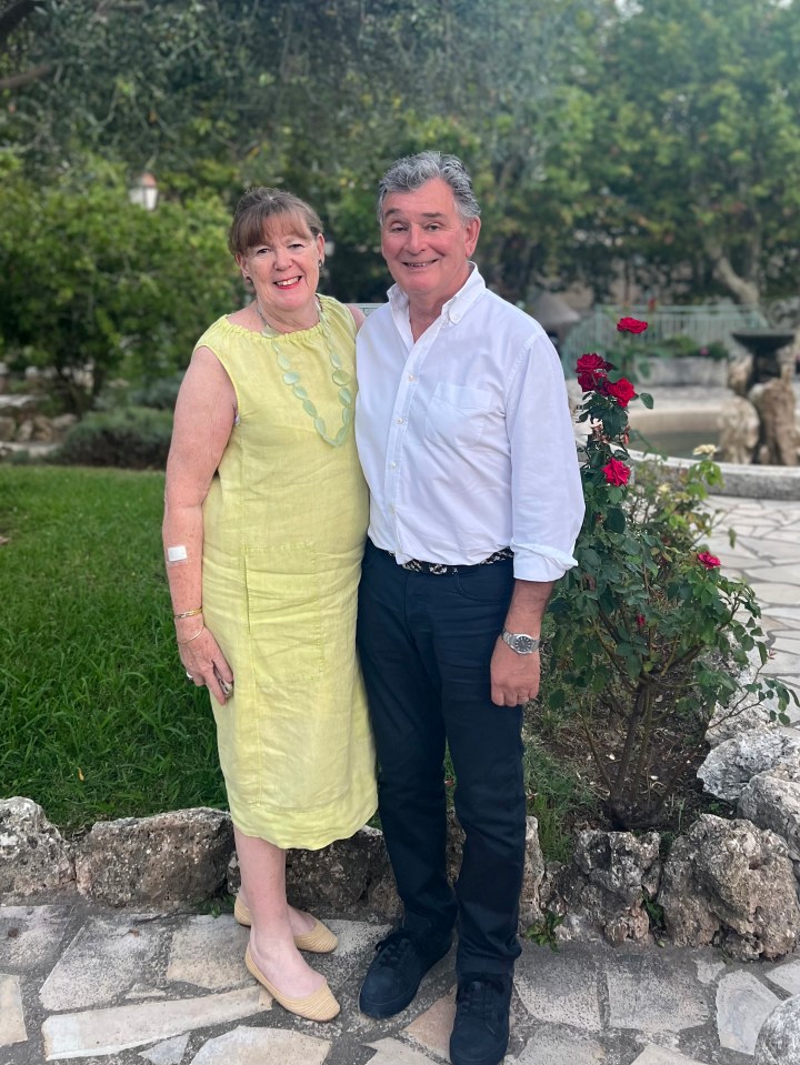 a man and a woman posing for a picture with roses in the background