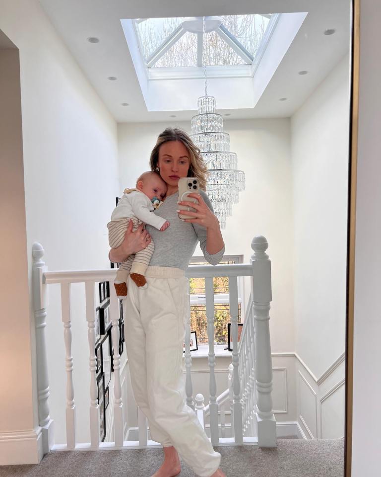 a woman is holding a baby and taking a selfie in front of a mirror