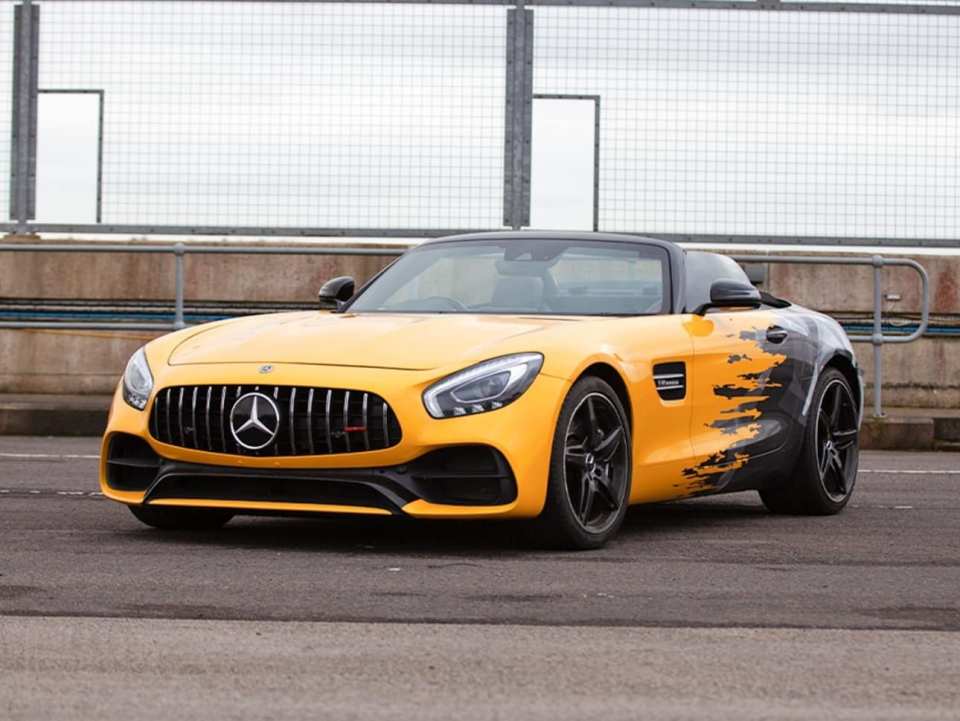 a yellow mercedes is parked in a parking lot