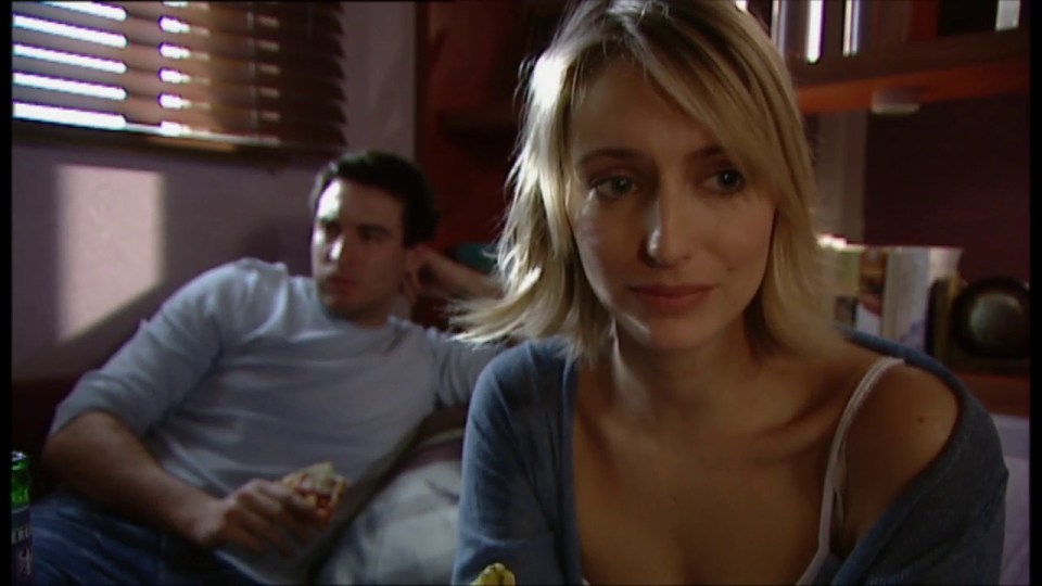 a man and a woman are sitting on a couch and the woman is looking at the camera